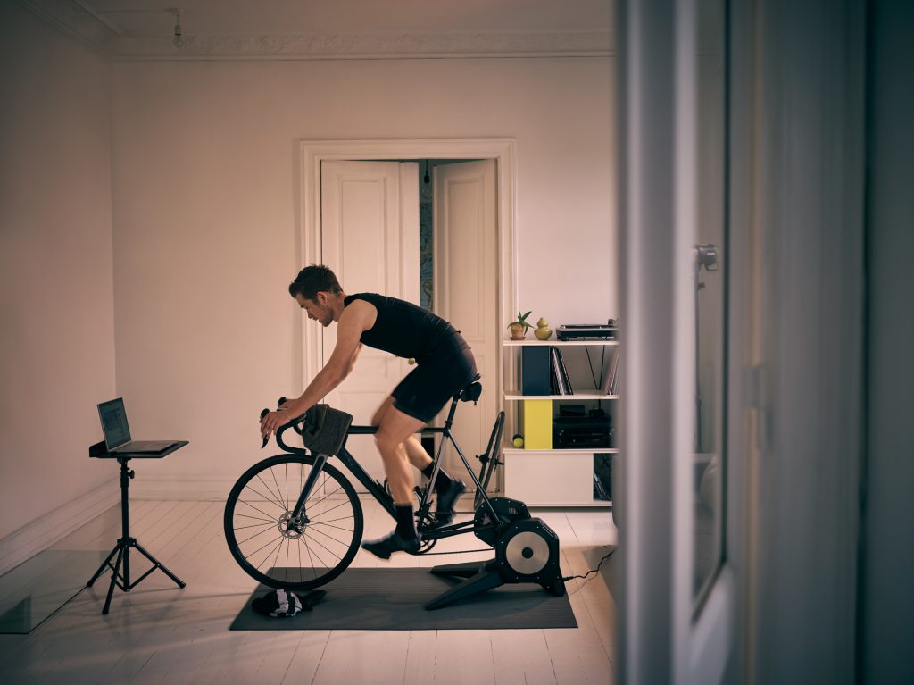 Shot of a young man working out on an exercise bike at home.