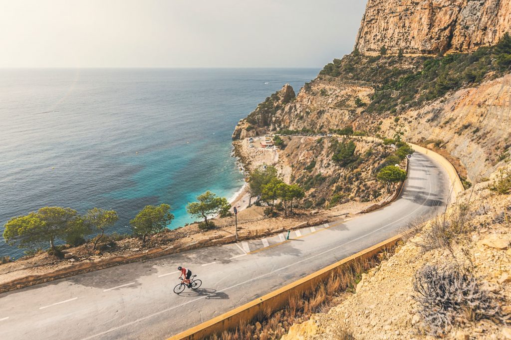 A man cycling along a beautiful coastal road.