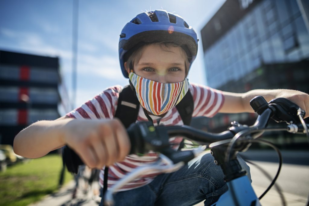 Little boy riding to school during COVID-19 pandemic.