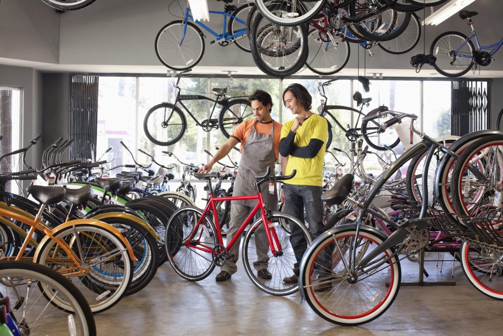 Bike shop owner helping customer choose bicycle.