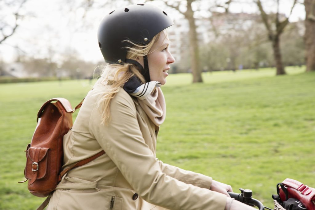 Female cyclist cycles through public park in city.