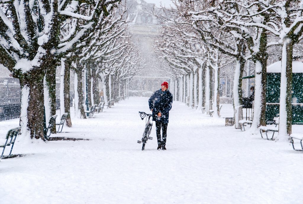A cyclist walking down a snowy path.